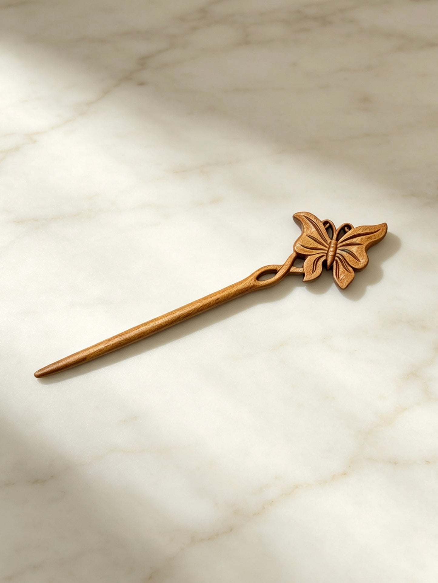 Butterfly carved hair stick displayed on a marble surface