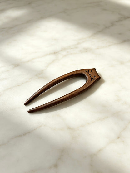 Cat double-prong sandalwood hair fork displayed on a marble surface