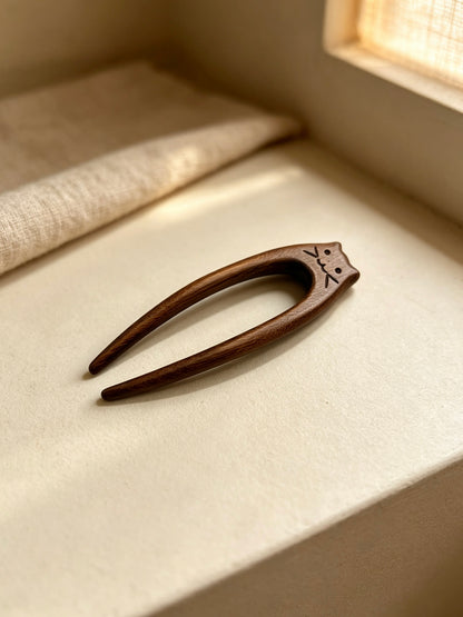 Cat double-prong sandalwood hair fork displayed on a light fabric surface