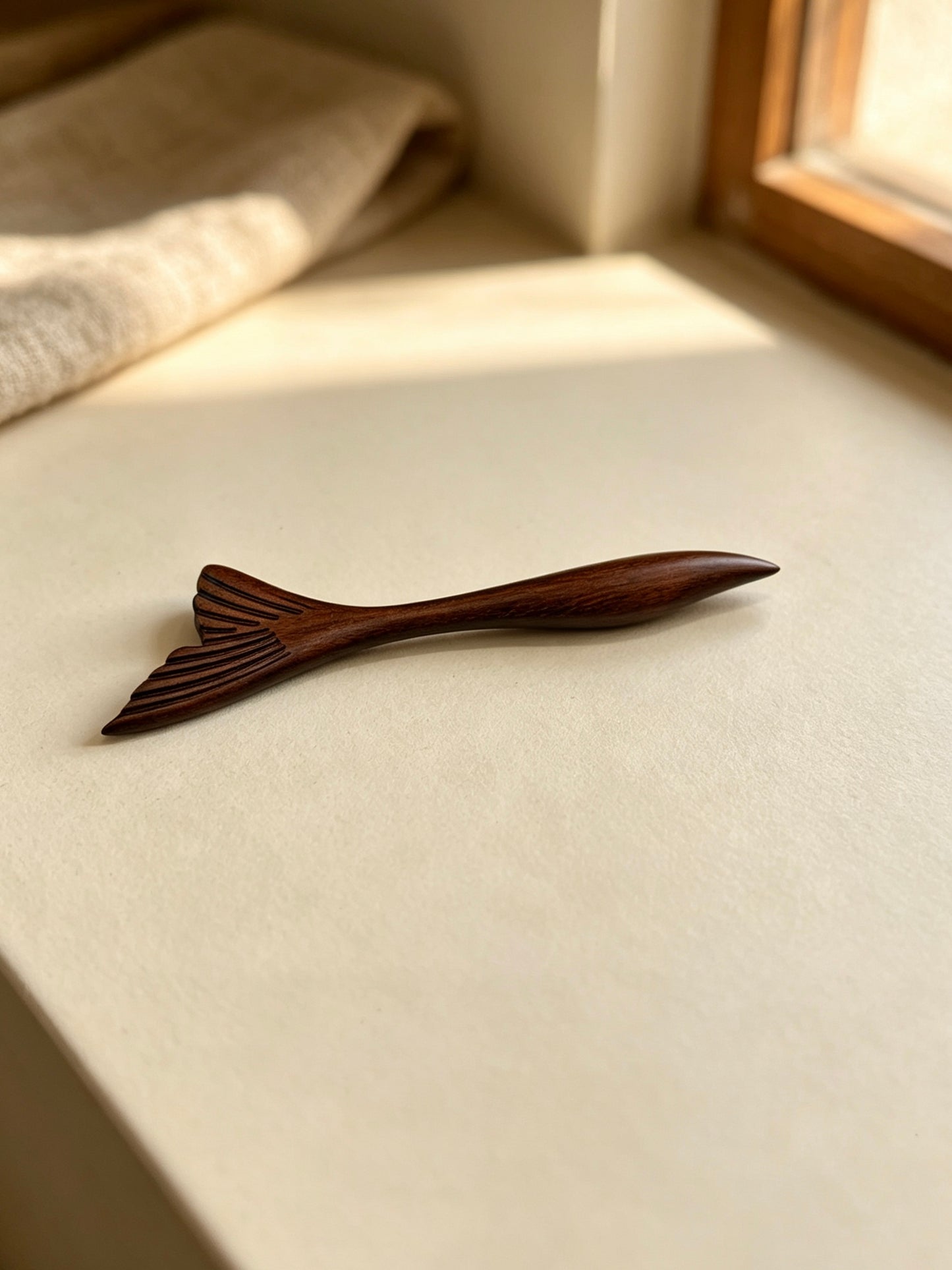 Fish tail sandalwood hair stick displayed on a light surface