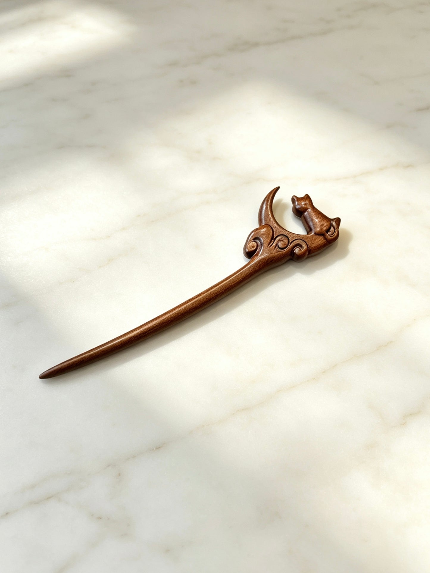 Moon gazing cat sandalwood hair stick displayed on a marble surface