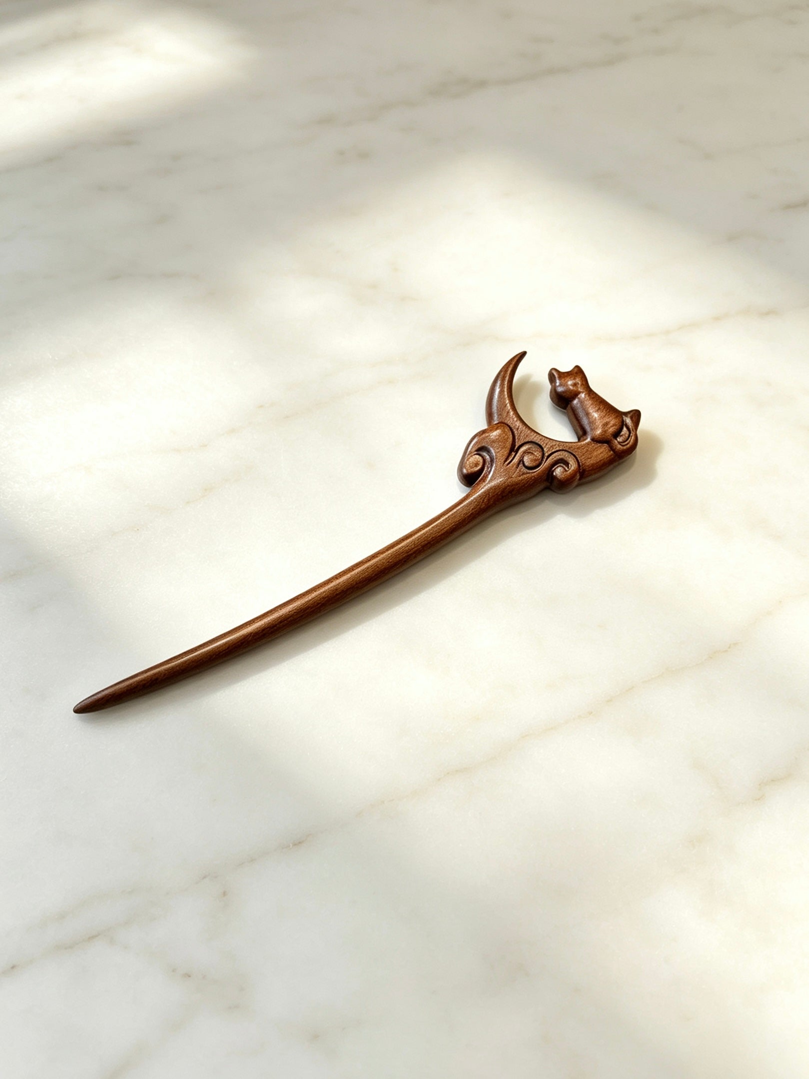 Moon gazing cat sandalwood hair stick displayed on a marble surface
