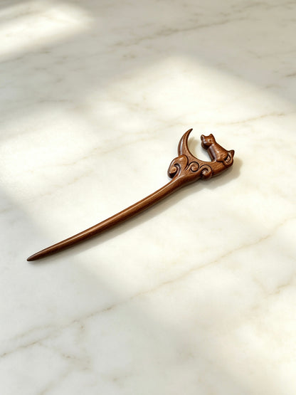 Moon gazing cat sandalwood hair stick displayed on a marble surface