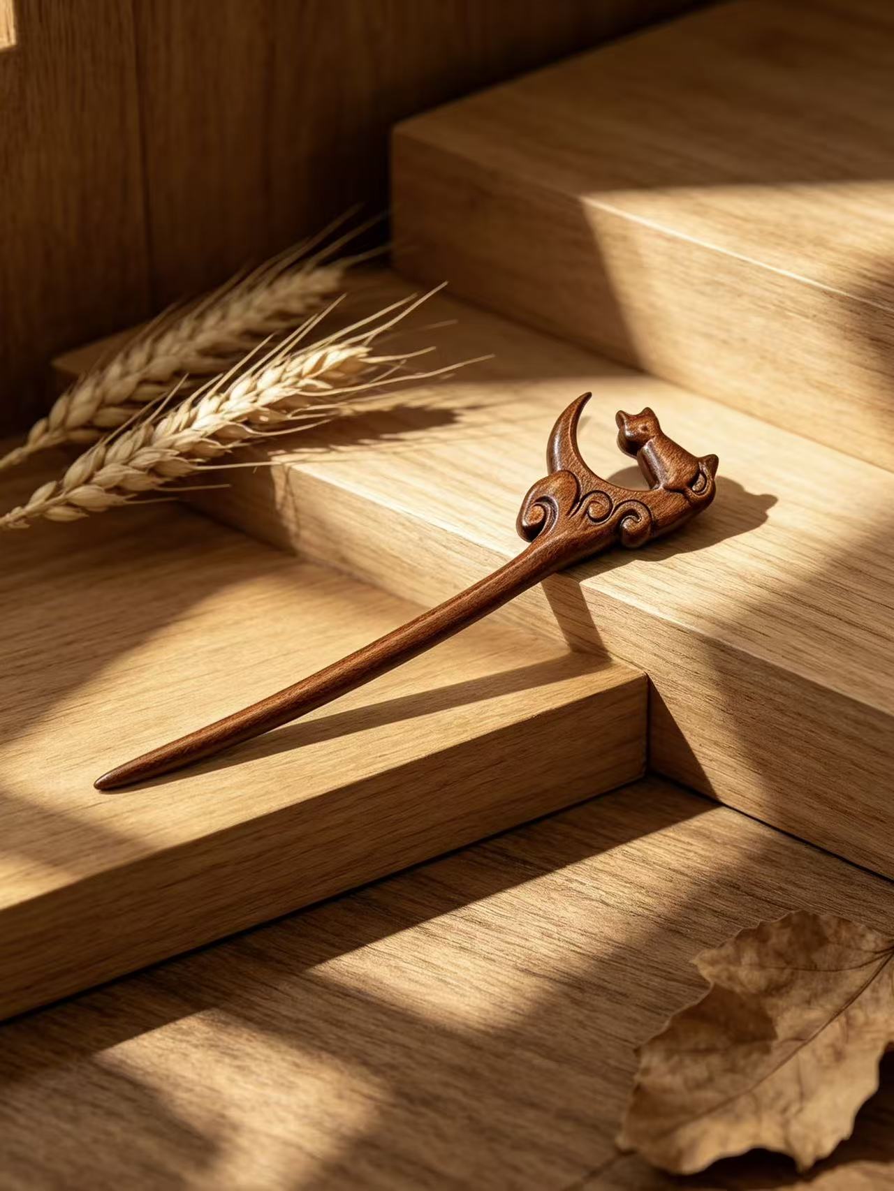 Moon gazing cat sandalwood hair stick displayed on a wooden surface with wheat