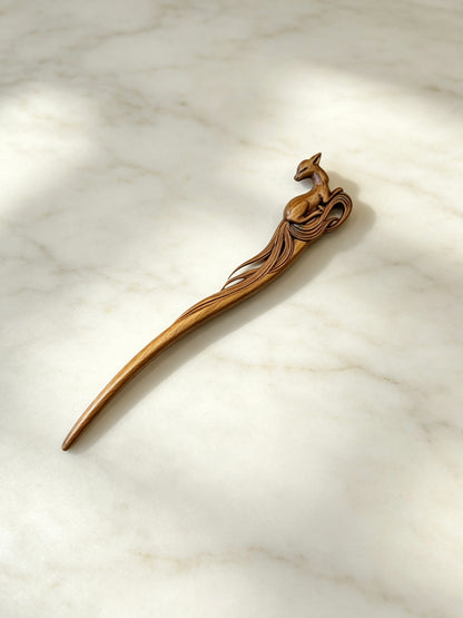 Sandalwood hair stick with a carved deer motif displayed on a marble surface