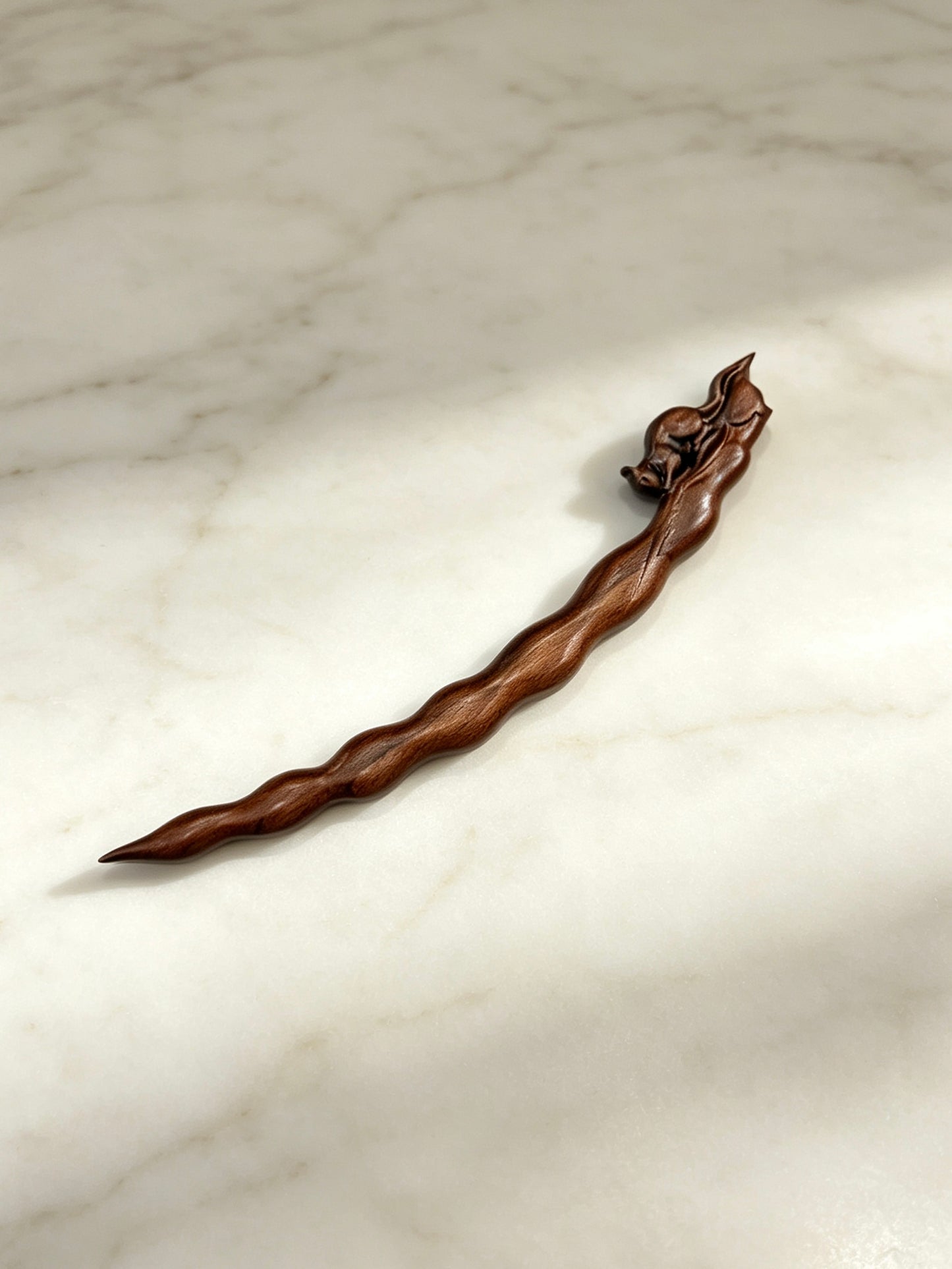 Squirrel peapod sandalwood hair stick displayed on a marble surface