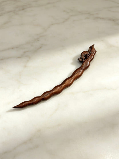 Squirrel peapod sandalwood hair stick displayed on a marble surface